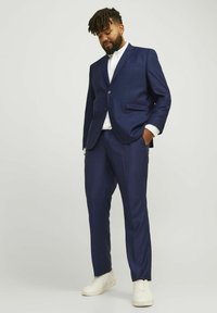 Costume marine avec une veste ajustée et un pantalon droit ; fabriqué en tissu lisse, avec une fermeture à un bouton et deux poches devant.