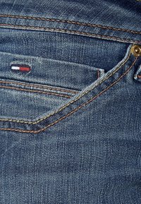 Jeans i denim med en bleknad blå tvätt, kontrasterande sömmar, en liten röd-vit-blå logotyp på bakfickan och en klassisk femficksdesign.