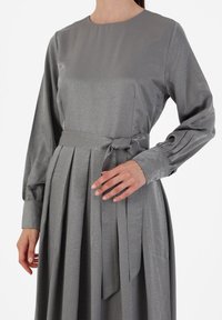 Gray dress with long puff sleeves, round neckline, pleated skirt, and a tied waist belt. Smooth, shiny fabric with subtle texture.