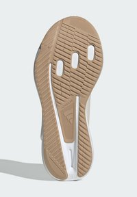Sneakerzool in beige en wit, met een structuurpatroon voor grip, drie ventilatiegaten en een reliëfmerk "ADIWEAR."