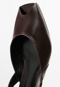 Chaussure ouverte en cuir bordeaux avec un design carré, affichant une silhouette épurée et un intérieur noir. Détails cousus le long des bords.
