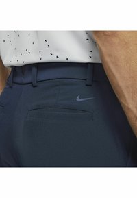 Mornarsko plave atletske hlače s glatkom teksturom, koje imaju stražnji džep i diskretni Nike logo tamnoplave boje na pojasu.