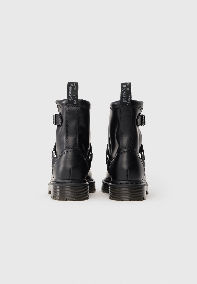 Schwarze Lederstiefeletten mit glatter Oberfläche, ausgestattet mit einem Schnallendetail, gerippten Sohlen und Ziehlaschen für ein einfaches An- und Ausziehen.