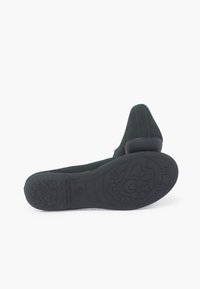 Zapato de ante verde oscuro con tacón bajo y suela de goma texturizada que presenta patrones de flores y corazones, resaltando el agarre y la comodidad.