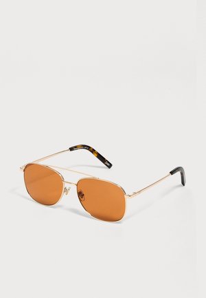 Goldgerahmte Flieger-Sonnenbrille mit orangefarbenen Gläsern und schwarzen Schildpatt-Bügelenden auf weißem Hintergrund.