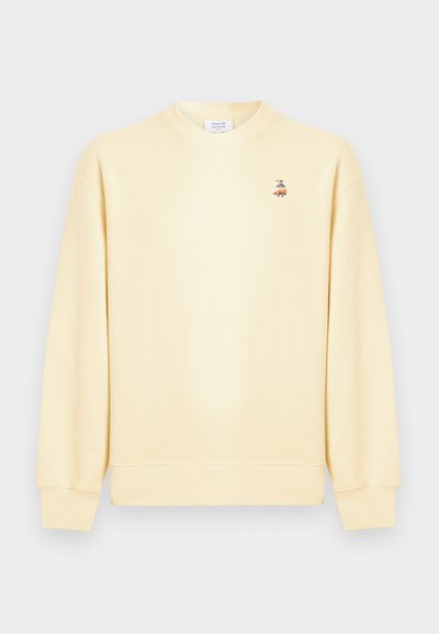 Μπεζ φούτερ με στρογγυλή λαιμόκοψη και μακριά μανίκια, με μικρό κεντημένο λογότυπο αλεπούς στο αριστερό στήθος.