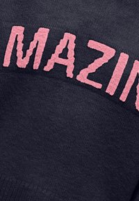 Tumši pelēkas krāsas džemperis ar tekstu "AMAZING" maigi rozā krāsā. Adījuma faktūra, nedaudz pārāk liela piegriezuma un ribota apakšdaļa.