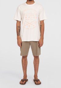 Vit T-shirt med rund halsringning och ljus korallfärgad grafisk tryck, tillsammans med tan-färgade shorts och bruna flip-flop-sandaler. Har korta ärmar och en avslappnad passform.