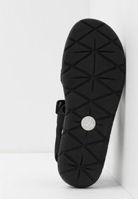 Sandalo nero con suola in gomma caratterizzato da un design testurizzato e un logo circolare. Cinturino regolabile per una vestibilità sicura.