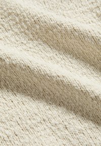 Tessuto color crema intrecciato con una superficie strutturata, caratterizzato da un motivo sottile e una sensazione morbida e fibrosa. Ideale per tappezzeria o decorazioni.