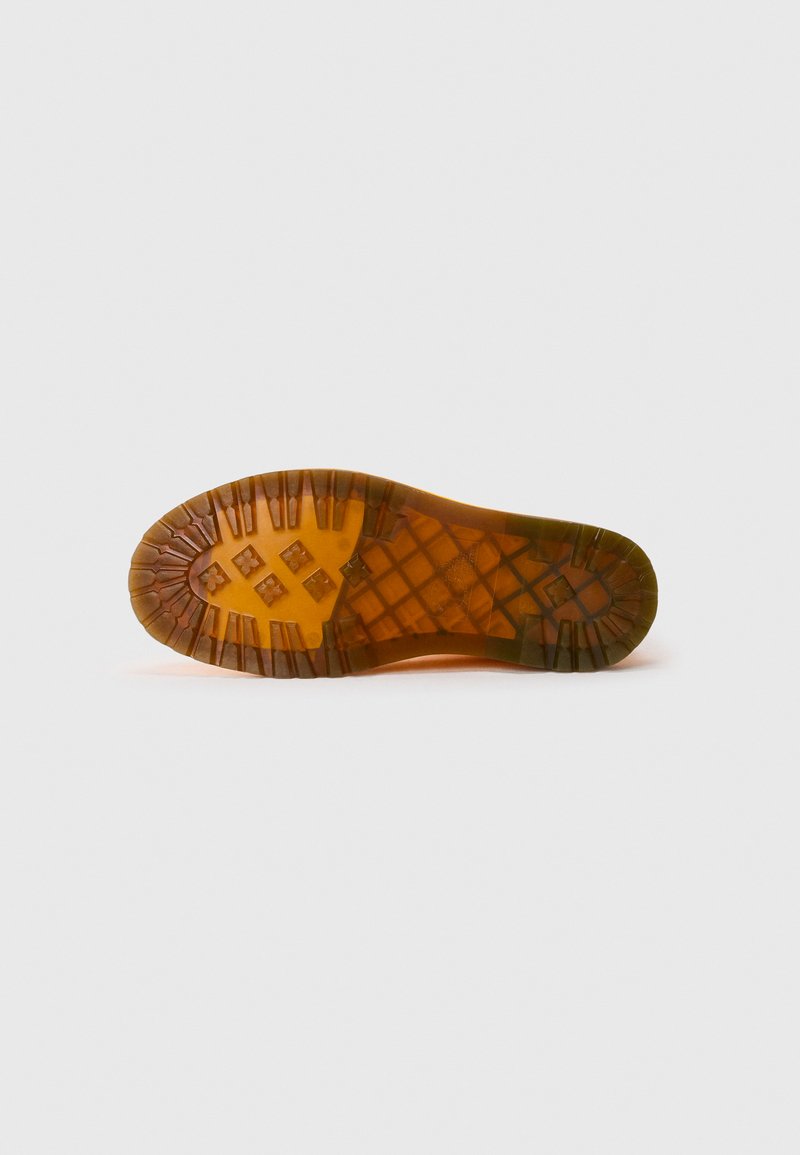 Rubber shoe sole in tan, featuring a textured surface with a diamond pattern and circular grooves for traction.