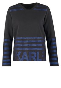 Top negro de manga larga con escote en V, que presenta paneles de malla a rayas azules y "KARL" impreso en letras grandes en el dobladillo. Textura suave.