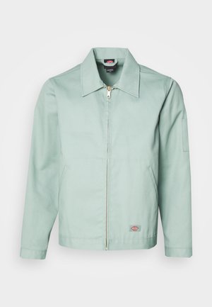 Hellgrüne Jacke aus Baumwolle mit einem Frontreißverschluss, spitzem Kragen und zwei seitlichen Taschen. Mit einem Patch-Logo an der linken unteren Seite.