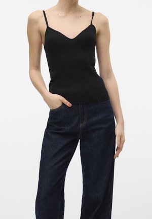 Top sin mangas negro de canalé con tirantes delgados, escote en V, diseño ajustado, combinado con jeans de mezclilla azul oscuro de corte recto.