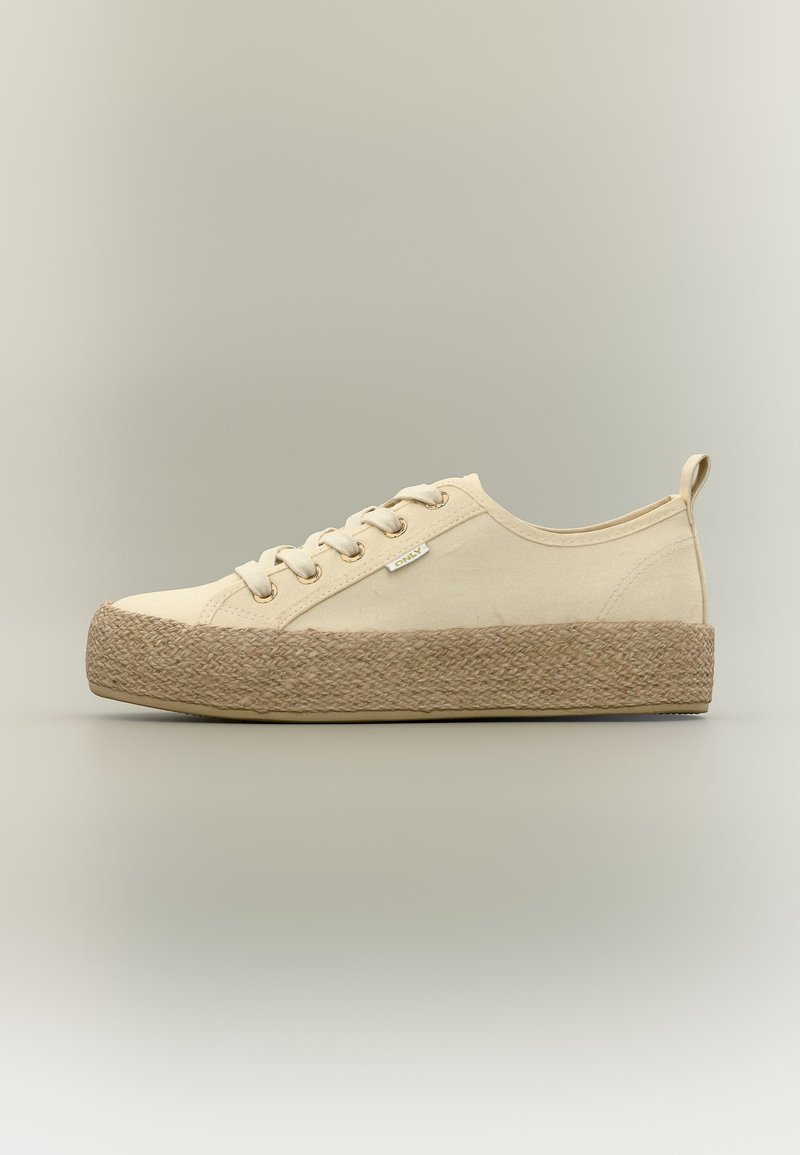 Μπεζ πάνινο αθλητικό παπούτσι με πλεγμένη σόλα από σχοινί τζούτας και δέσιμο με κορδόνια σε ουδέτερο φόντο.