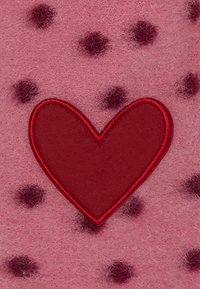 Roze viltstof met donkerdere roze stippen, met een centraal rood hartapplicatie omrand met rode stiksel.