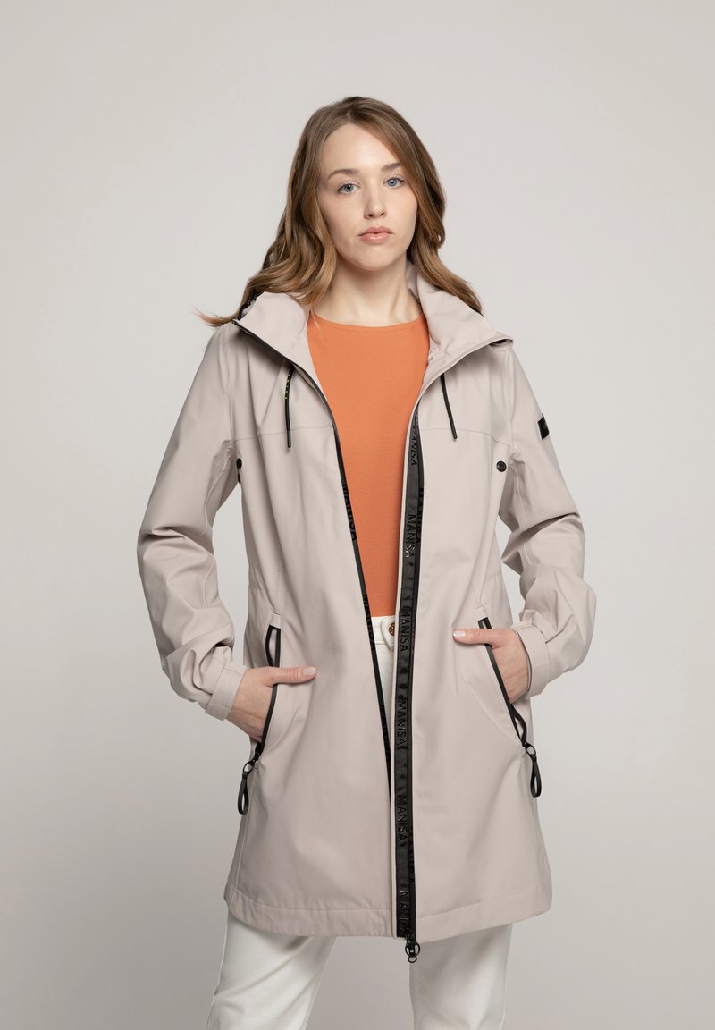 Lichtbeige waterdichte jas met een capuchon, rits aan de voorkant, twee zijzakken en verstelbare koordjes. Heeft zwarte accenten en logo-details.