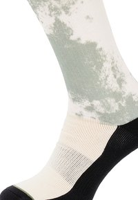 Ponožky po kolená v svetlej smotane a zelenej farbe, s potlačou tie-dye. Základ je čierny s rebrovanou textúrou na manžete.