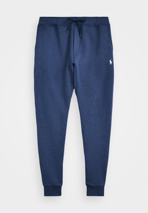 Pantalons de survêtement bleu marine en tissu doux, avec une taille réglable par cordon, des poignets côtelés et un petit logo blanc sur la cuisse gauche.