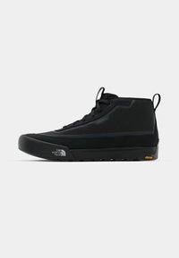 Chaussure mi-haute noire avec une tige en tissu texturé, semelle en caoutchouc et marque Vibram. Comprend des lacets et une languette pour un enfilage facile.