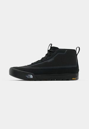 Black mid-top shoe with a textured fabric upper, rubber outsole, and Vibram branding. Features laces and pull tab for easy wear.