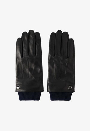 Gants en cuir noir avec un poignet tricoté côtelé bleu marine, comportant quatre coutures sur chaque doigt et un petit logo en métal au niveau du poignet.