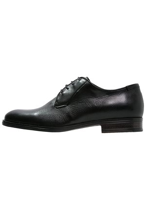 Scarpa formale Oxford da uomo in pelle nera con allacciatura chiusa e tacco basso a strati, mostrata di profilo su sfondo bianco.