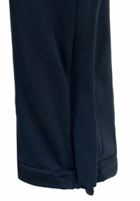 Close-up van een donkerblauwe stoffen broekspijp met een omgevouwen zoom en zichtbare stikseldetails.