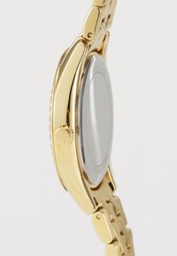 Goldfarbenes Edelstahl-Uhr mit einem hochglanzpolierten Gehäuse, einem strukturierten Armband und einem runden Ziffernblatt. Besitzt eine Krone und ein minimalistisches Design ohne sichtbare Markierungen.
