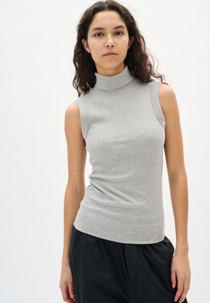 Top grigio senza maniche con collo alto realizzato in tessuto a costine; design aderente con una texture liscia e collo alto; abbinato a pantaloni neri dal taglio morbido.