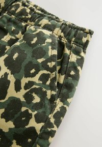 Pantaloni cargo in fantasia leopardata verde e beige. Realizzati in cotone, presentano una tasca laterale e una cintura elastica per il massimo comfort.