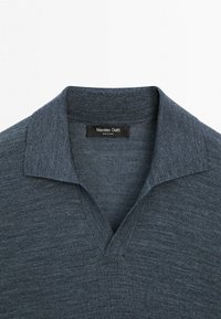 Polo en maille gris foncé avec un col côtelé et une ouverture en V, montrant l'étiquette de marque "Massimo Dutti" à l'intérieur du col.