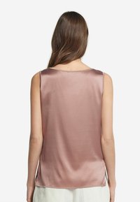 Sukienka bez rękawów wykonana z satyny w delikatnym różowym kolorze, charakteryzująca się luźnym krojem, okrągłym dekoltem oraz bocznymi rozcięciami zapewniającymi swobodę ruchów. Gładka, błyszcząca tekstura.