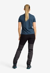 Dark blue cotton t-shirt, black and gray multi-panel pants, and black trekking shoes. The outfit features a practical, fitted design.