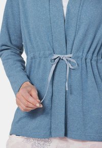 Hellblauer, strukturierter Cardigan mit Bindegürtel, der lange Ärmel und einen lockeren Schnitt hat. Der Stoff hat ein weiches, gemütliches Aussehen.