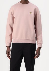 Roze sweatshirt met ribgebreide mouwen en zoom. Bevat een klein geel vlinderlogo op de borst. Gemaakt van zacht, structuurstof.
