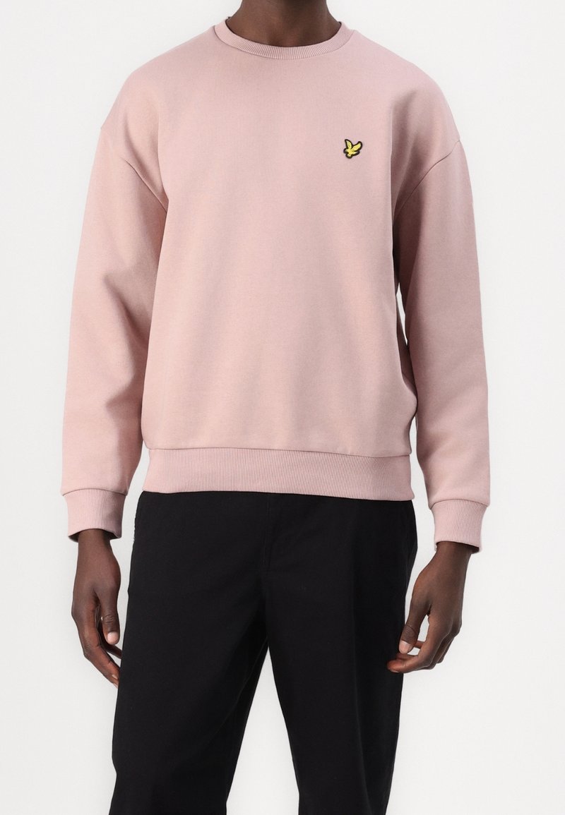 Roze sweatshirt met ribgebreide mouwen en zoom. Bevat een klein geel vlinderlogo op de borst. Gemaakt van zacht, structuurstof.