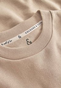 Maglione in cotone beige con un col rib ribattuto e un'etichetta con "Colours & Sons". Texture morbida con cuciture lisce e uniformi.