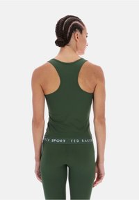 Olíva zöld sportos ujjatlan felső, versenyháttal, sima textúrával és kontrasztos fehér "Ted Baker Sport" logóval a derékrészen.
