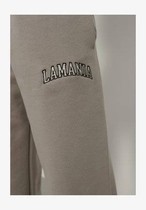 Szürke melegítőnadrág, amelyen hímzett "LAMANIA" logó található a bal combján. Az anyag simának tűnik, enyhén elasztikus textúrával.