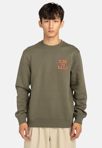 Sudadera verde oliva de corte relajado, con puños y cuello acanalados, y un gráfico en naranja que dice "RIDE THE RAILS" en el pecho.
