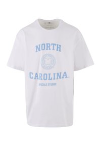 Hvid bomulds T-shirt med lyseblå tekst "NORTH CAROLINA" og "UPSCALE STUDIOS" samt et rundt emblemdesign i midten.