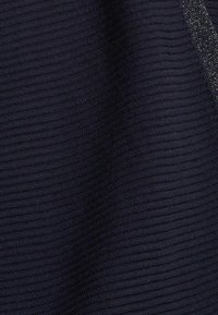 Tissu côtelé bleu marine foncé avec de fines lignes horizontales et une bande argentée scintillante le long du bord, montrant les détails de la texture et du motif.