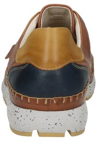 Zapato de cuero con un upper marrón y acentos en azul marino, y una suela con puntitos blancos. Incluye detalles de costura y un talón acolchado.