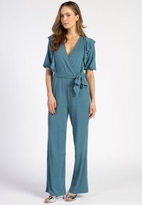 Teal wikkel jumpsuit met korte gerimpelde mouwen, een strik taille en wijde pijpen. Gladde textuur met een diepe V-hals.