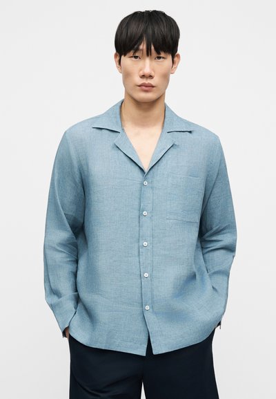 Ανοιχτό μπλε κοντομάνικο πουκάμισο με γιακά τύπου notch, κουμπιά στο μπροστινό μέρος, μια τσέπη στο στήθος και άνετη εφαρμογή, κατασκευασμένο από υφή υφάσματος.