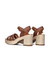 Bruine leren sandalen met hakken, met een gekruisd ontwerp, verstelbare enkelbandjes en een textuur van espadrille-achtige wiggen.