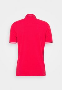 Polo rouge à manches courtes avec bordure rayée sur le col et les manches, vu de dos sur un fond clair uni.