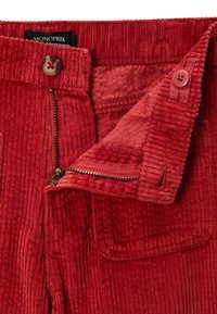 Pantalons en velours côtelé rouge avec une fermeture éclair et un bouton, texture côtelée et une petite poche avant.