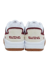 Fehér tornacipő, bézs színű irhabőr sarokmerevítővel, bordó díszítésekkel és hátul dombornyomott "Ewing" logóval. Gumi talp a tapadásért.